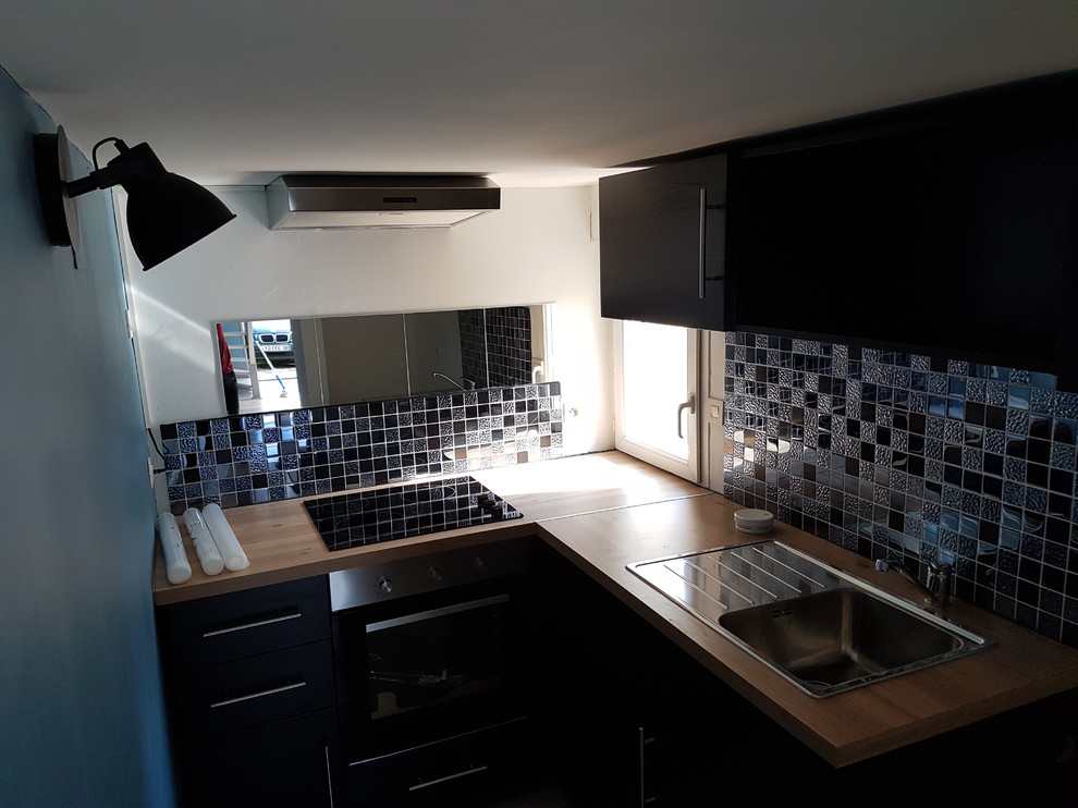 Idéer för att renovera ett litet funkis kök, med en enkel diskho, svarta skåp, träbänkskiva, svart stänkskydd, stänkskydd i mosaik, svarta vitvaror, vinylgolv och grått golv