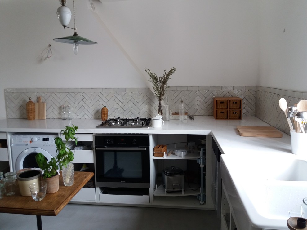 Immagine di una cucina a L bohémian chiusa e di medie dimensioni con paraspruzzi bianco, paraspruzzi con piastrelle in ceramica, pavimento in cemento, nessuna isola e pavimento grigio