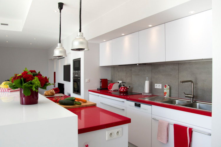 Inredning av ett modernt mellanstort röd linjärt rött kök med öppen planlösning, med en undermonterad diskho, luckor med profilerade fronter, vita skåp, laminatbänkskiva, grått stänkskydd, rostfria vitvaror och en köksö