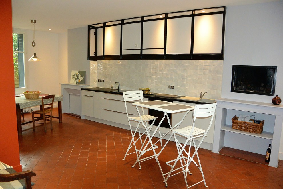 Exemple d'une grande cuisine ouverte linéaire tendance avec des portes de placard blanches, un plan de travail en quartz, une crédence blanche, une crédence en terre cuite, tomettes au sol et îlot.