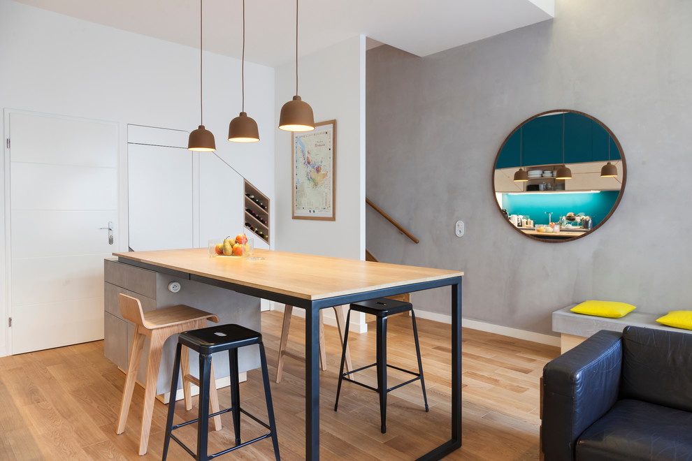 Modern inredning av ett mellanstort kök, med en enkel diskho, luckor med profilerade fronter, skåp i ljust trä, bänkskiva i betong, glaspanel som stänkskydd, integrerade vitvaror, ljust trägolv, en köksö och blått stänkskydd