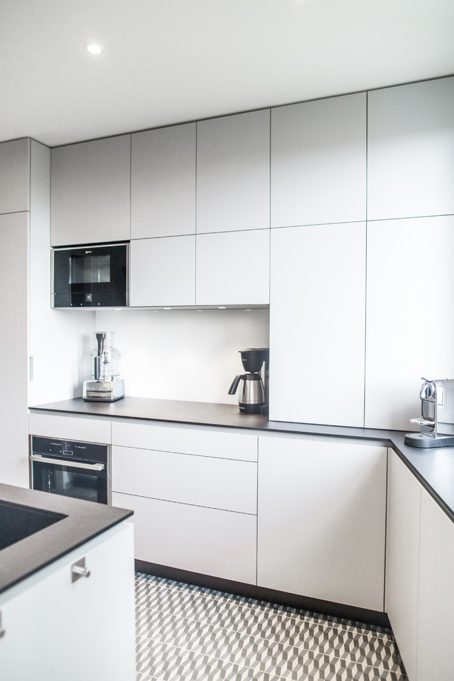 Photo of a medium sized contemporary enclosed kitchen in Angers with a submerged sink, flat-panel cabinets, laminate countertops, white splashback, glass sheet splashback, integrated appliances, ceramic flooring and no island.