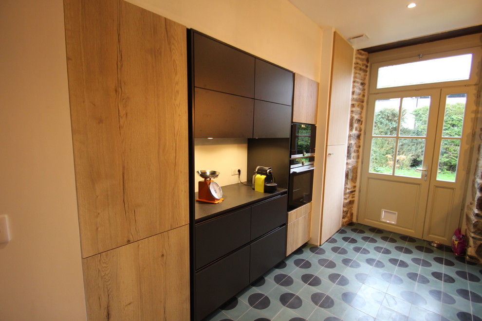 This is an example of a medium sized industrial galley enclosed kitchen in Rennes with an integrated sink, flat-panel cabinets, black cabinets, granite worktops, black splashback, black appliances, cement flooring, turquoise floors and black worktops.