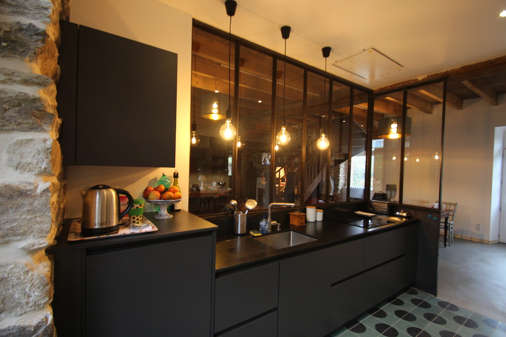 Mid-sized urban galley cement tile floor and turquoise floor enclosed kitchen photo in Rennes with an integrated sink, flat-panel cabinets, black cabinets, granite countertops, black backsplash, black appliances and black countertops