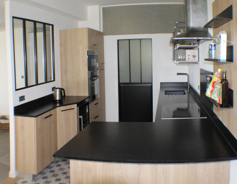 Idéer för att renovera ett mellanstort industriellt svart svart kök, med en integrerad diskho, luckor med profilerade fronter, skåp i ljust trä, granitbänkskiva, svart stänkskydd, klinkergolv i keramik, en halv köksö och flerfärgat golv