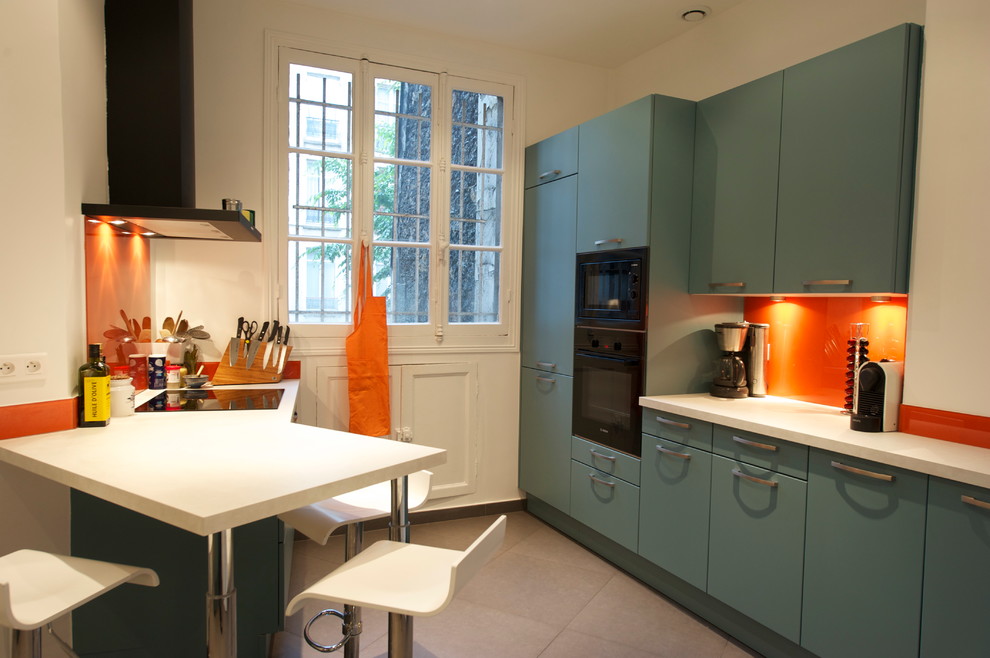 パリにあるお手頃価格の広いモダンスタイルのおしゃれなキッチン (シングルシンク、フラットパネル扉のキャビネット、青いキャビネット、ラミネートカウンター、オレンジのキッチンパネル、ガラス板のキッチンパネル、黒い調理設備、セラミックタイルの床) の写真