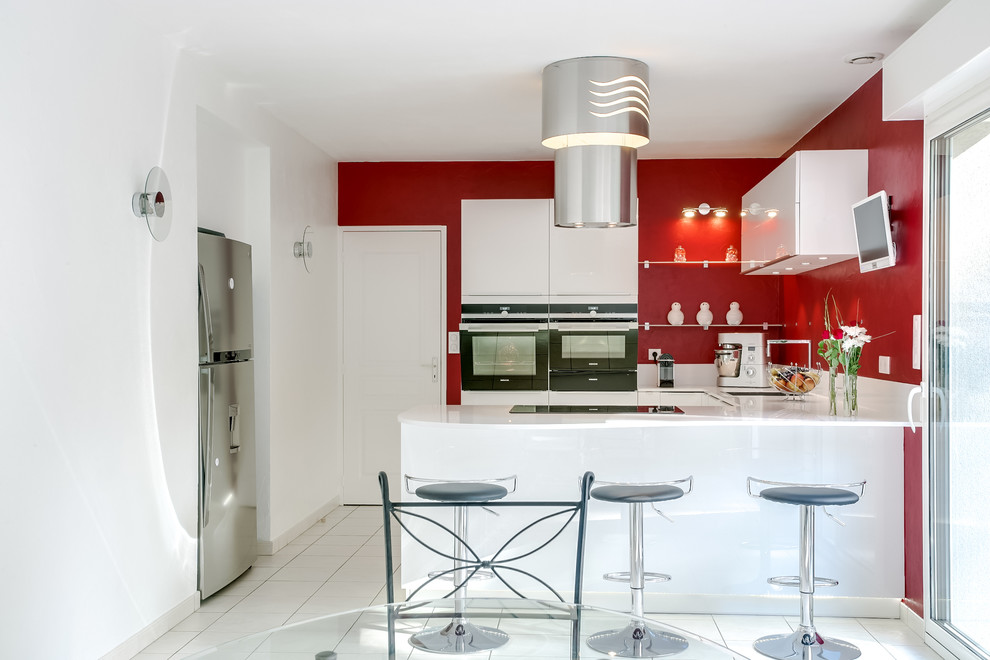 Imagen de cocina actual pequeña con fregadero bajoencimera, armarios con paneles lisos, puertas de armario blancas, salpicadero rojo y electrodomésticos blancos