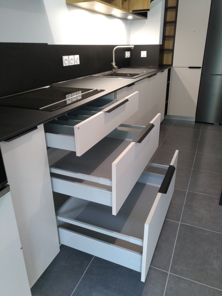 This is an example of a large contemporary l-shaped kitchen/diner in Other with a built-in sink, beaded cabinets, grey cabinets, laminate countertops, black splashback, black appliances, ceramic flooring, an island, grey floors and black worktops.