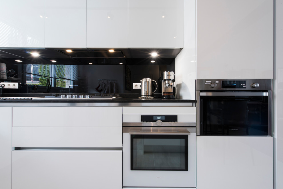 Aménagement d'une cuisine ouverte contemporaine en L de taille moyenne avec un plan de travail en granite, une crédence noire et îlot.