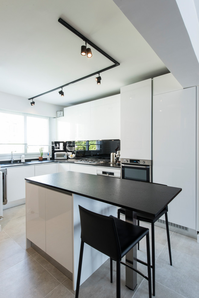 Idée de décoration pour une cuisine ouverte design en L de taille moyenne avec un plan de travail en granite, une crédence noire et îlot.