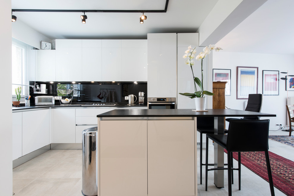 Свежая идея для дизайна: угловая кухня-гостиная среднего размера в современном стиле с гранитной столешницей, черным фартуком и островом - отличное фото интерьера