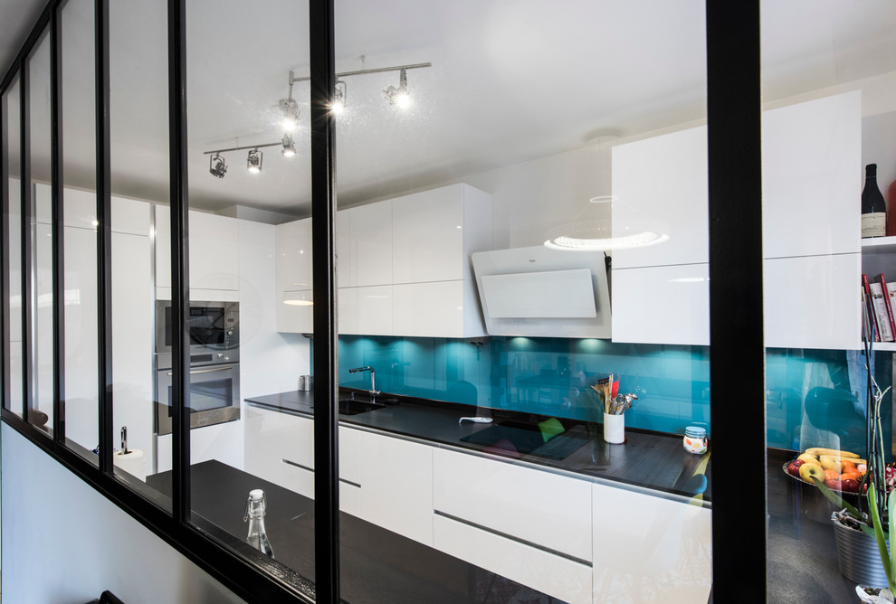Medium sized contemporary u-shaped kitchen in Paris with a submerged sink, granite worktops, blue splashback and ceramic flooring.