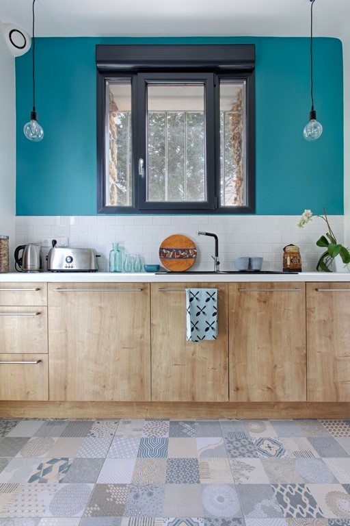 Inspiration for a medium sized scandinavian l-shaped enclosed kitchen in Paris with a single-bowl sink, flat-panel cabinets, light wood cabinets, laminate countertops, white splashback, ceramic splashback, stainless steel appliances, cement flooring, no island, multi-coloured floors and white worktops.