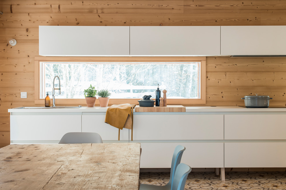 Medium sized contemporary single-wall kitchen/diner in Lyon with a double-bowl sink, flat-panel cabinets, white cabinets, multi-coloured floors, white worktops, beige splashback, wood splashback and ceramic flooring.