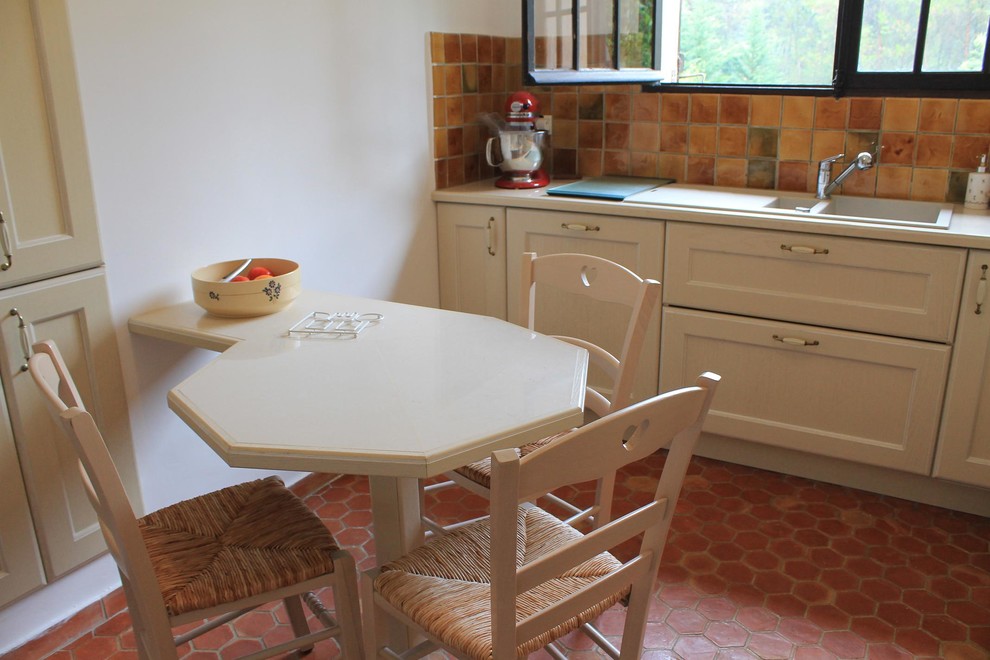 Klassisk inredning av ett avskilt, mellanstort l-kök, med en dubbel diskho, kaklad bänkskiva, flerfärgad stänkskydd, stänkskydd i keramik, rostfria vitvaror, klinkergolv i terrakotta och rött golv