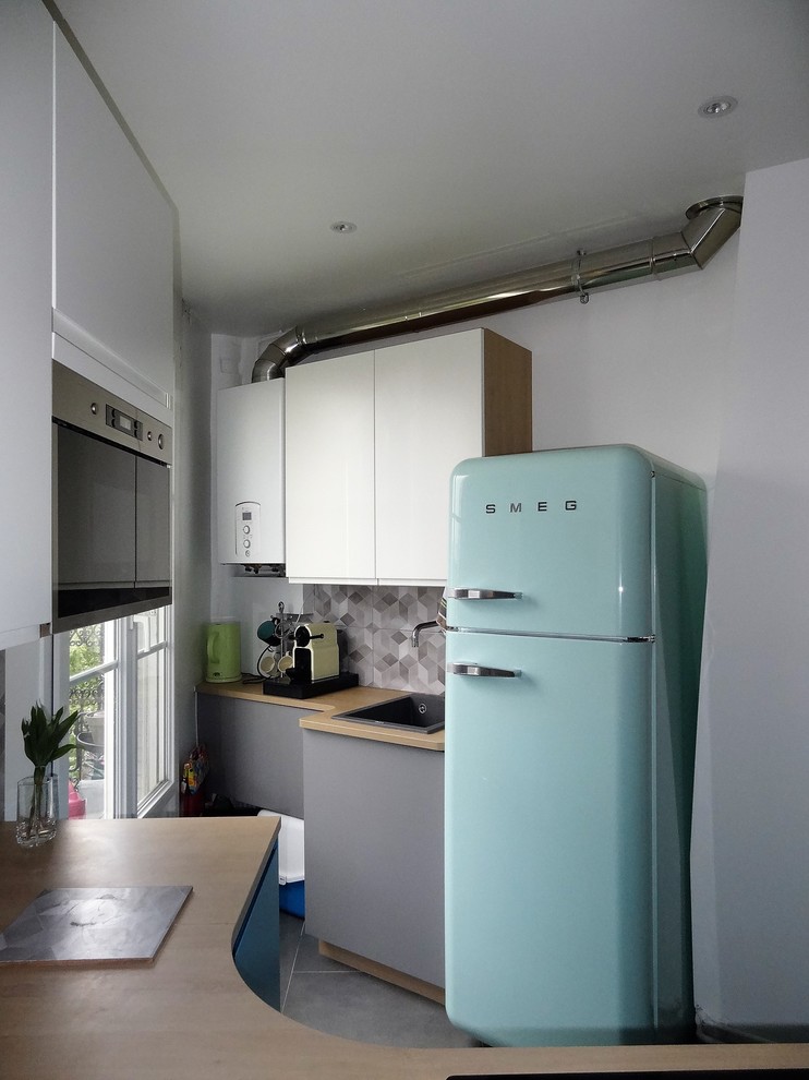 Example of a small danish l-shaped ceramic tile and gray floor eat-in kitchen design in Paris with an undermount sink, beaded inset cabinets, white cabinets, wood countertops, gray backsplash, ceramic backsplash, colored appliances and no island