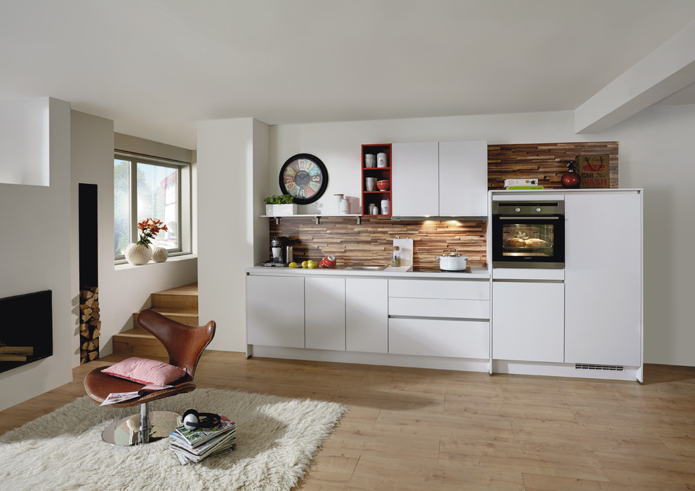 Пример оригинального дизайна: прямая кухня-гостиная среднего размера в скандинавском стиле с белыми фасадами и коричневым фартуком без острова