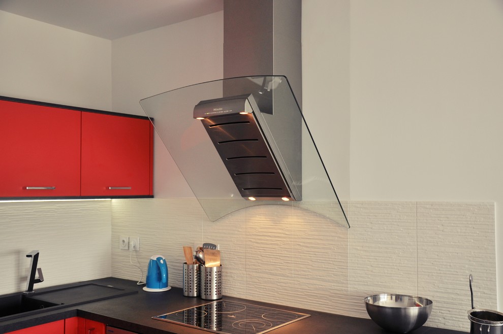 Ejemplo de cocina minimalista pequeña con fregadero bajoencimera, puertas de armario rojas, salpicadero negro, electrodomésticos de acero inoxidable y suelo de baldosas de porcelana