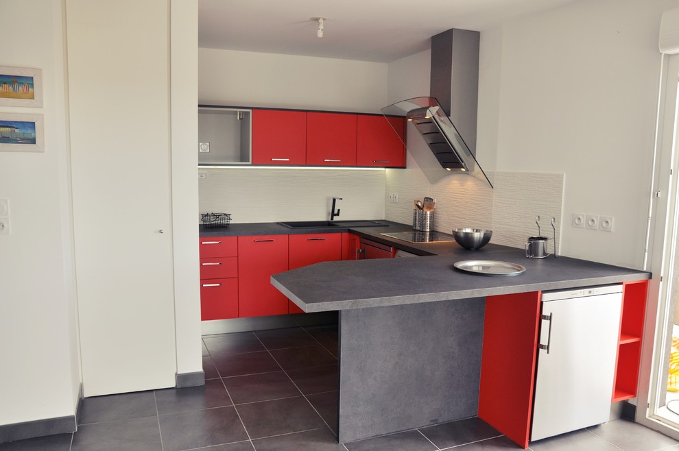 Modelo de cocina moderna pequeña con fregadero bajoencimera, puertas de armario rojas, salpicadero negro, electrodomésticos de acero inoxidable y suelo de baldosas de porcelana