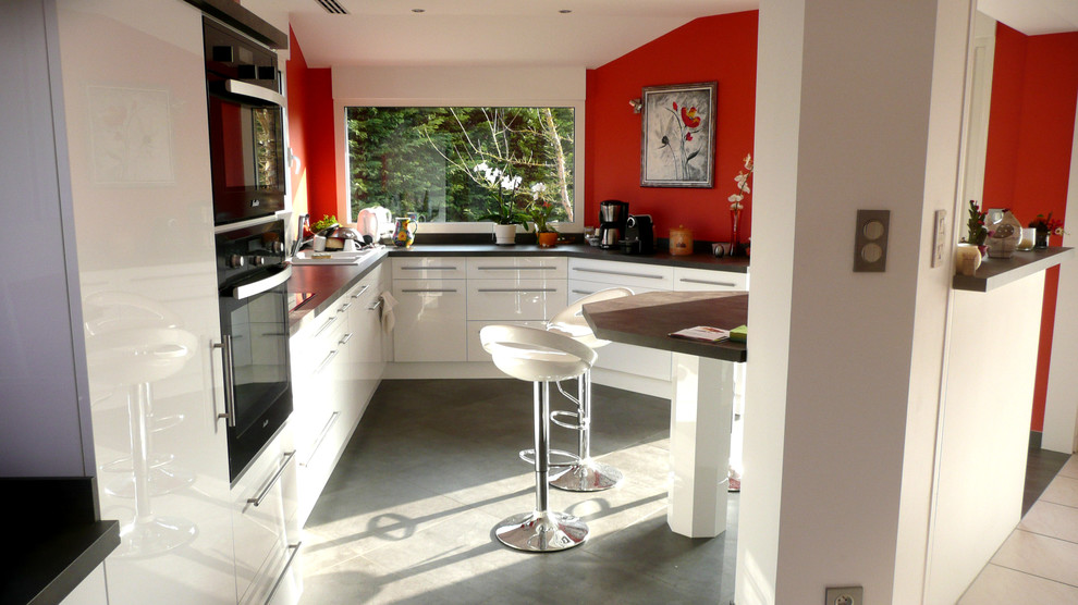 Foto di una grande cucina moderna con lavello a doppia vasca, ante lisce, ante bianche, top in laminato, paraspruzzi nero, elettrodomestici neri e pavimento con piastrelle in ceramica