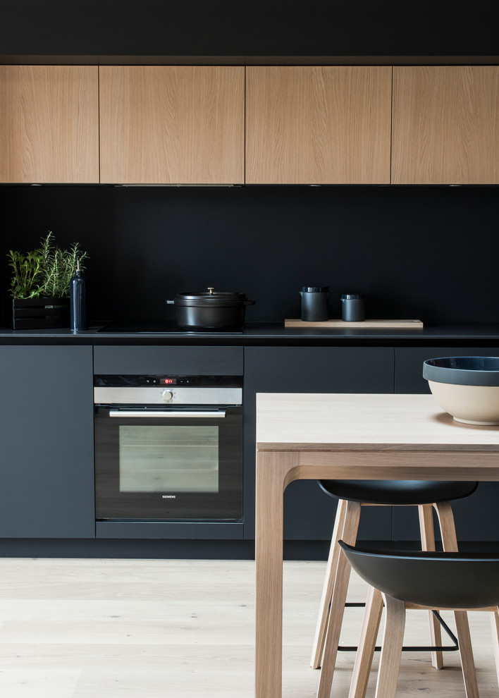Réalisation d'une cuisine ouverte linéaire design de taille moyenne avec des portes de placard noires, une crédence noire, parquet clair et un sol beige.