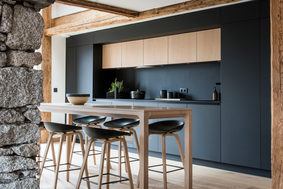 Idées déco pour une cuisine ouverte linéaire contemporaine de taille moyenne avec des portes de placard noires, une crédence noire, parquet clair et un sol beige.