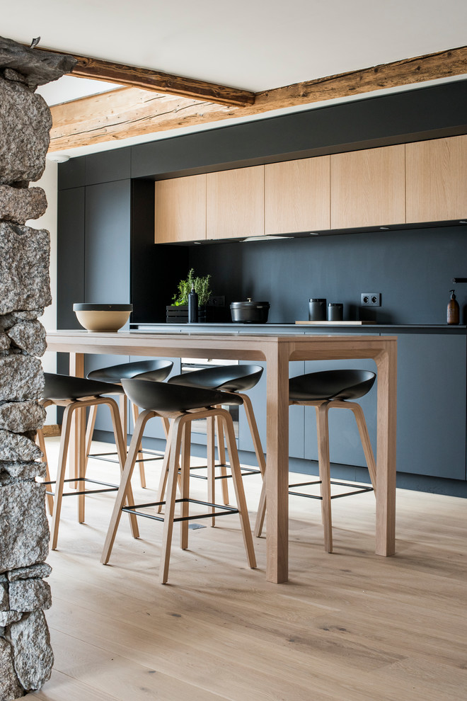 Offene, Einzeilige, Mittelgroße Moderne Küche mit schwarzen Schränken, Küchenrückwand in Schwarz, hellem Holzboden und beigem Boden in Lyon
