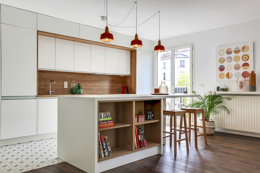 Design ideas for a large midcentury single-wall open plan kitchen in Paris with white cabinets, laminate countertops, integrated appliances, cement flooring, an island, flat-panel cabinets, brown splashback, wood splashback and multi-coloured floors.