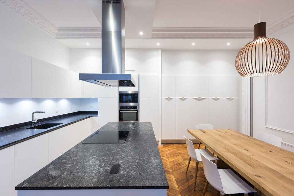 Immagine di una grande cucina contemporanea con lavello sottopiano, ante bianche e elettrodomestici neri