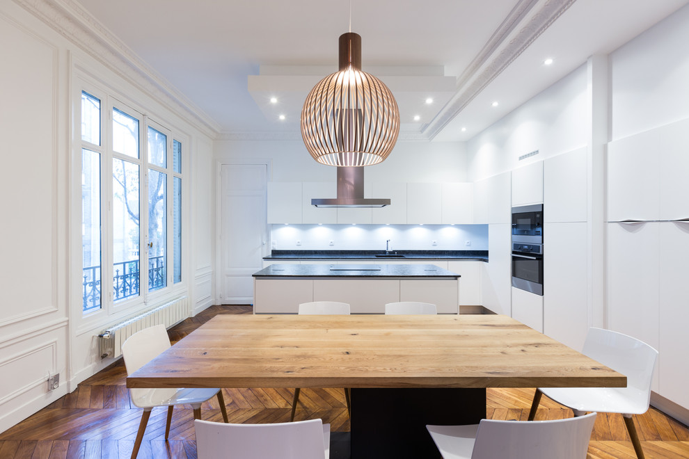 Offene, Zweizeilige, Große Moderne Küche mit Unterbauwaschbecken, weißen Schränken, schwarzen Elektrogeräten und Kücheninsel in Paris