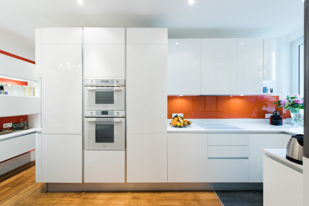 Design ideas for a medium sized modern u-shaped open plan kitchen in Paris with an integrated sink, beaded cabinets, white cabinets, quartz worktops, orange splashback, glass tiled splashback and integrated appliances.