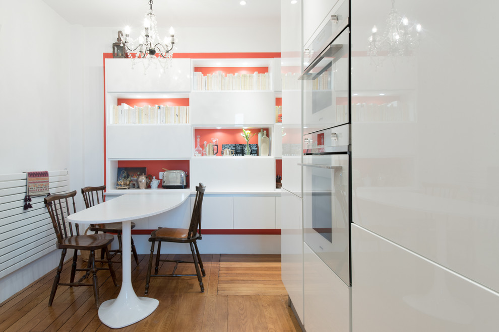 Idées déco pour une cuisine américaine encastrable et parallèle moderne de taille moyenne avec un placard à porte affleurante, des portes de placard blanches et parquet clair.