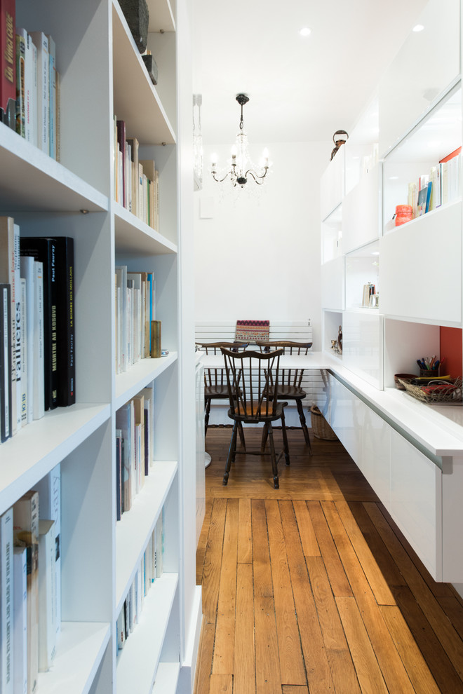 Zweizeilige, Mittelgroße Moderne Wohnküche mit Kassettenfronten, weißen Schränken, Elektrogeräten mit Frontblende und hellem Holzboden in Paris