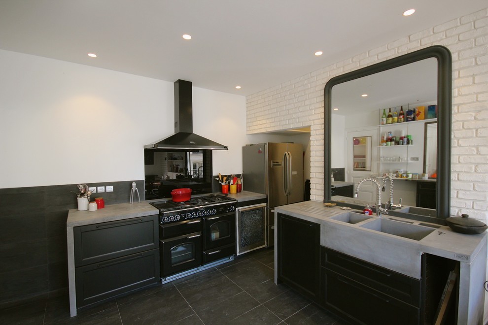 Large urban u-shaped slate floor and black floor enclosed kitchen photo in Paris with a double-bowl sink, beaded inset cabinets, black cabinets, concrete countertops, black backsplash, slate backsplash, black appliances, two islands and gray countertops