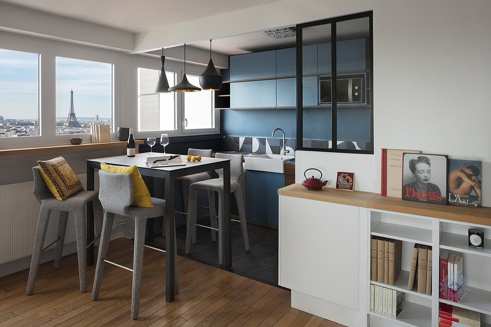 Kleine Moderne Wohnküche in L-Form mit Waschbecken, blauen Schränken, Arbeitsplatte aus Fliesen, Küchenrückwand in Blau, Rückwand aus Zementfliesen, Küchengeräten aus Edelstahl, grauem Boden und blauer Arbeitsplatte in Paris