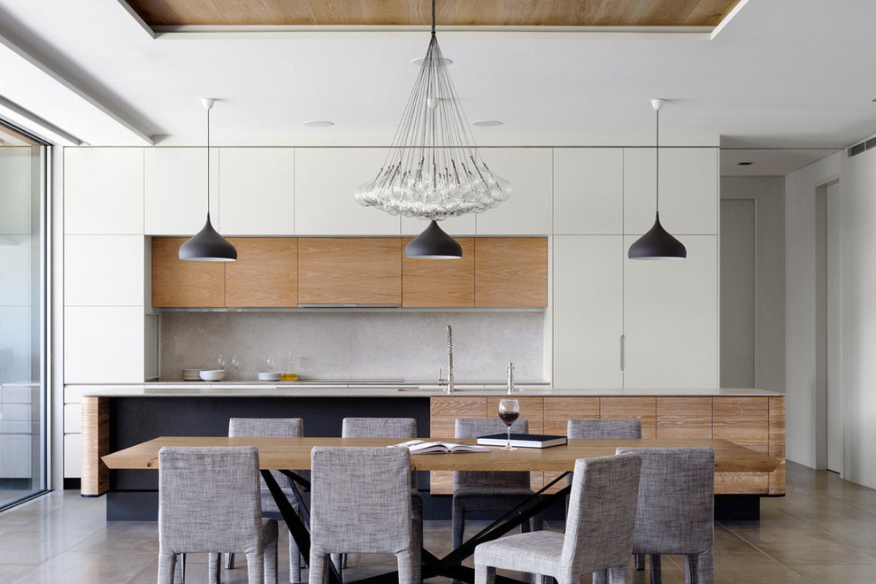 Aménagement d'une cuisine contemporaine en bois clair avec un placard à porte plane, une crédence grise, îlot et un sol gris.