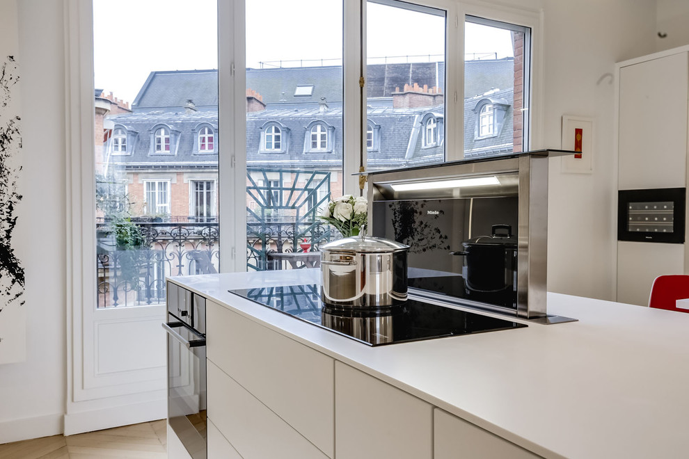 Example of a huge trendy light wood floor and beige floor open concept kitchen design in Paris with an undermount sink, flat-panel cabinets, white cabinets, mirror backsplash, paneled appliances and an island