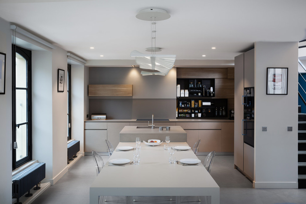 Inspiration for a modern concrete floor and gray floor open concept kitchen remodel in Paris with an integrated sink, beige cabinets, solid surface countertops, beige backsplash, glass sheet backsplash, an island and beige countertops