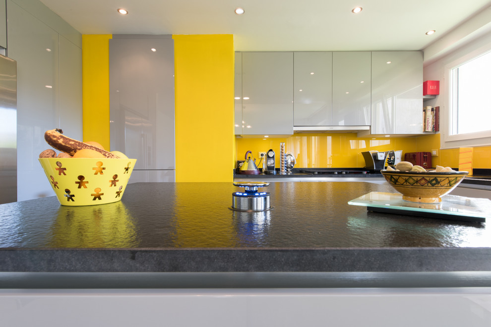 Medium sized bohemian u-shaped kitchen/diner in Paris with an integrated sink, beaded cabinets, grey cabinets, granite worktops, yellow splashback, glass tiled splashback, stainless steel appliances and an island.