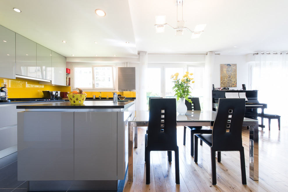 Foto di una cucina eclettica di medie dimensioni con lavello integrato, ante a persiana, ante grigie, top in granito, paraspruzzi giallo, paraspruzzi con piastrelle di vetro e elettrodomestici in acciaio inossidabile