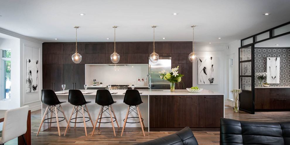 Inspiration for a large contemporary galley open plan kitchen in Montreal with a double-bowl sink, flat-panel cabinets, glass sheet splashback, stainless steel appliances, medium hardwood flooring, quartz worktops and a breakfast bar.