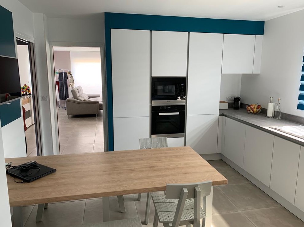 Inspiration for a large contemporary u-shaped enclosed kitchen in Le Havre with white cabinets, concrete worktops, grey splashback, stainless steel appliances, ceramic flooring, no island, beige floors and grey worktops.