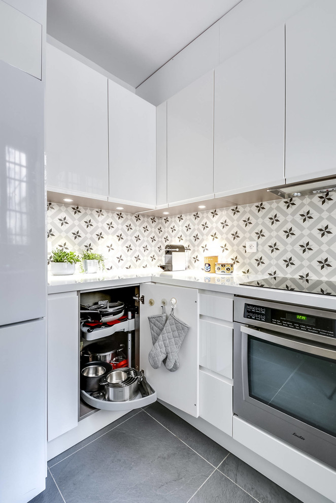 Modern inredning av ett mellanstort grå grått kök, med vita skåp, laminatbänkskiva, stänkskydd i cementkakel, klinkergolv i porslin, en köksö, grått golv, en nedsänkt diskho, släta luckor, flerfärgad stänkskydd och rostfria vitvaror