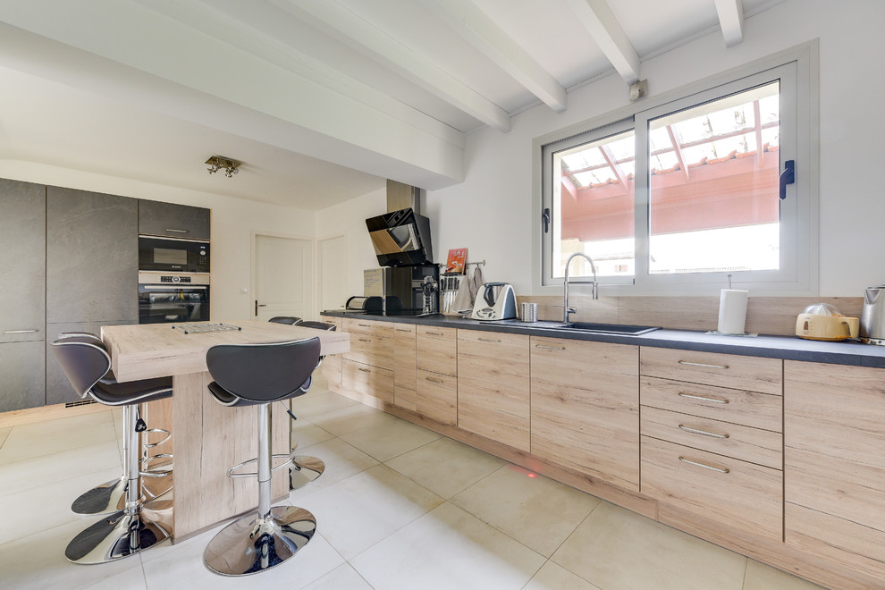 Photo of a large modern l-shaped enclosed kitchen in Bordeaux with a single-bowl sink, beaded cabinets, light wood cabinets, laminate countertops, wood splashback, black appliances, ceramic flooring, no island, white floors and grey worktops.