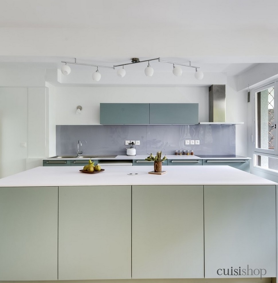 Inredning av ett modernt stort vit linjärt vitt kök och matrum, med en köksö, en dubbel diskho, släta luckor, gröna skåp, laminatbänkskiva, grått stänkskydd, glaspanel som stänkskydd, rostfria vitvaror, cementgolv och grönt golv