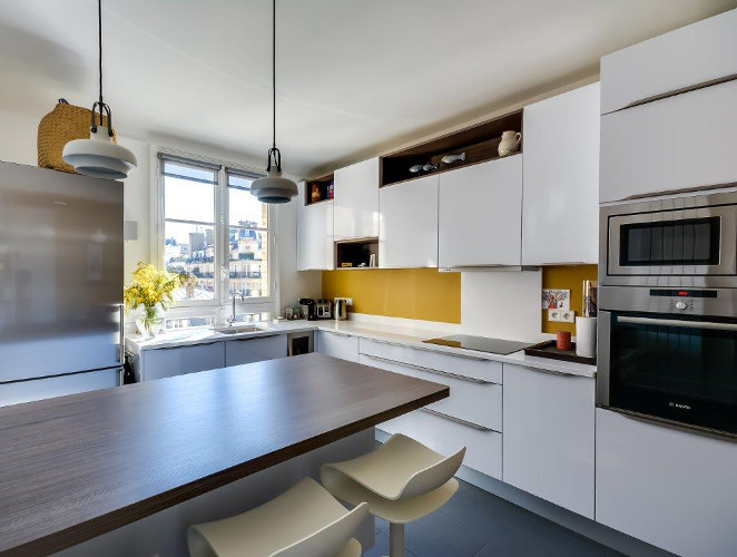 Exemple d'une cuisine scandinave en U fermée et de taille moyenne avec des portes de placard blanches, un plan de travail en quartz, une crédence blanche, un électroménager en acier inoxydable et îlot.