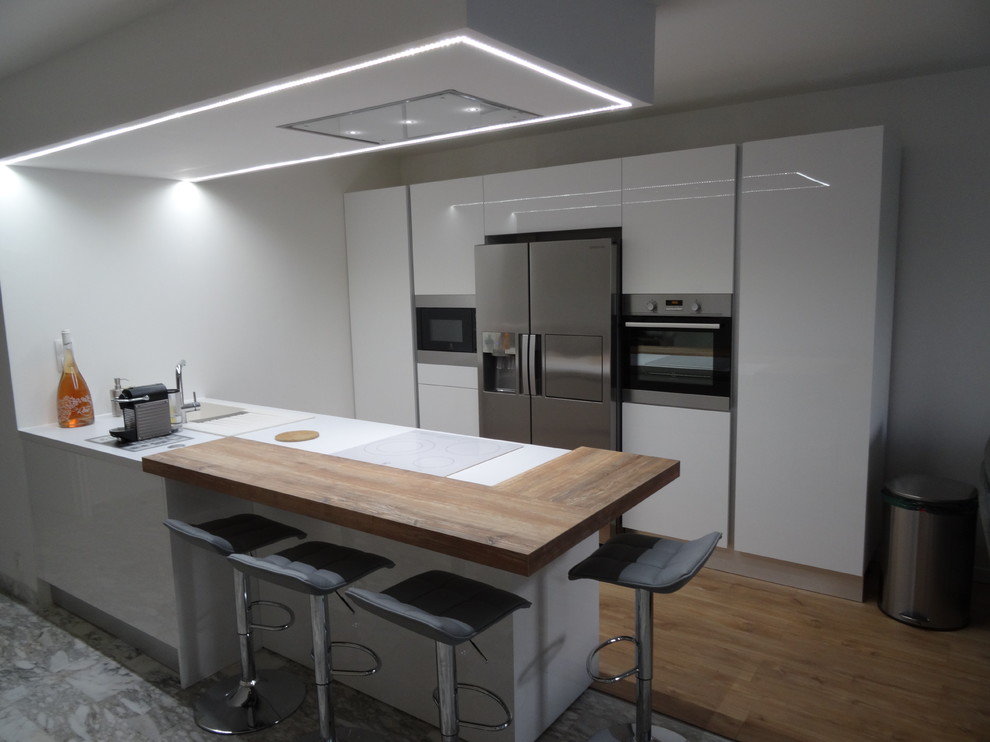 Medium sized modern galley open plan kitchen in Marseille with a submerged sink, beaded cabinets, white cabinets, laminate countertops, stainless steel appliances, marble flooring, an island and grey floors.