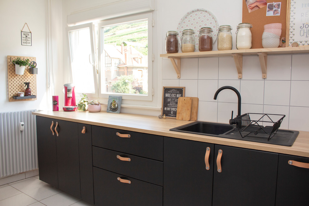Idee per una cucina scandinava di medie dimensioni con lavello a vasca singola, ante nere, paraspruzzi bianco, pavimento bianco, ante lisce, top in legno e top beige