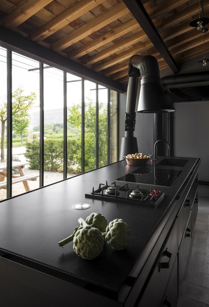 Cette image montre une cuisine urbaine avec une crédence noire, un électroménager noir, carreaux de ciment au sol, îlot et un sol gris.