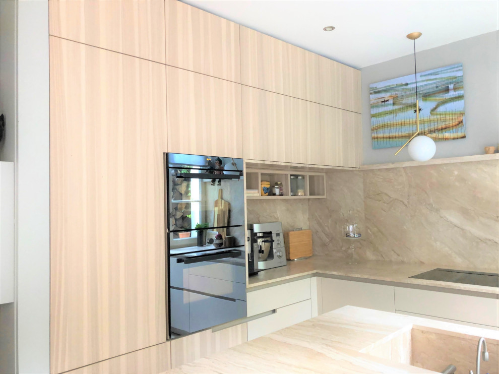 This is an example of a large contemporary l-shaped open plan kitchen in Paris with a single-bowl sink, beaded cabinets, beige cabinets, marble worktops, beige splashback, marble splashback, black appliances, light hardwood flooring, an island and beige worktops.